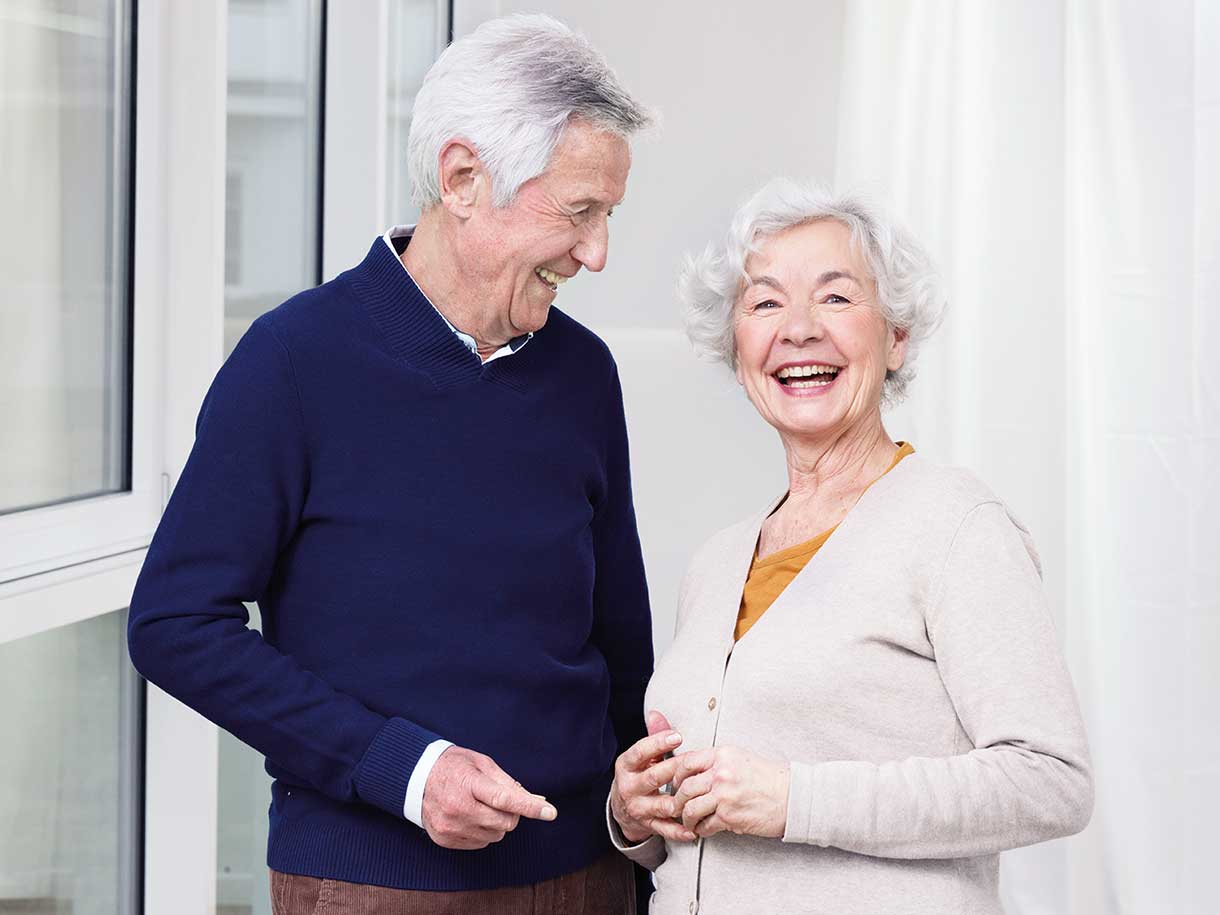 Egy mosolygó idős férfi és nő áll egymás mellett